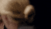 a close up of a woman 's face in a dark room with her hair in a bun .