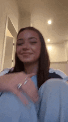 a woman is sitting on the floor with her eyes closed and smiling . she is wearing a bracelet on her wrist .