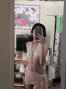 a woman in a bikini takes a selfie in front of a painting