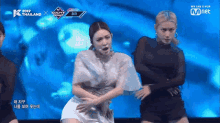 a woman in a white dress is dancing on a stage in front of a mnet logo .