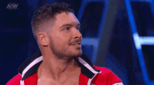 a man with a beard is wearing a red jacket and smiling while standing on a stage .