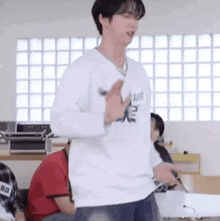 a man in a white sweater is dancing in a room with other people .