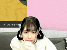 a girl with pigtails is sitting on a couch in front of a sign that says p