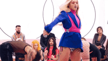 a woman in a blue and pink dress is dancing in front of a crowd of people .