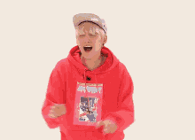 a young man in a red hoodie and hat is dancing .