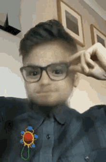 a young boy wearing glasses is making a funny face with his finger .