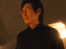 a man wearing glasses and a black shirt looks to his left