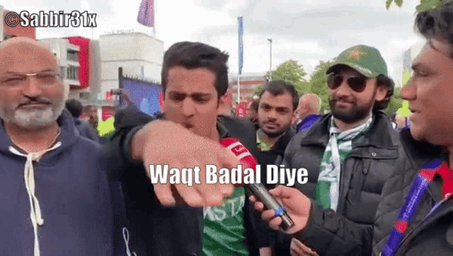 a man holding a microphone pointing at another man with the words waqt badal diye written below him