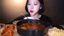 a woman is eating a bowl of soup with a fork