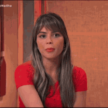 a woman is wearing a red shirt and a ring on her finger .