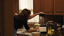 a woman is using a blender to make a smoothie in a kitchen