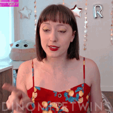 a woman wearing a red top with lemons on it stands in front of a balloon that says r