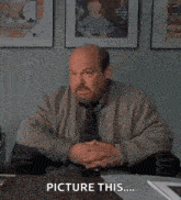 a man with a beard is sitting at a desk with his hands in the air and says `` picture this ... '' .