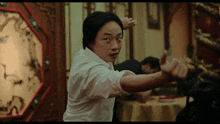 a man in a white shirt is practicing martial arts in front of a clock