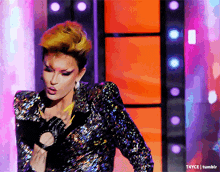 a woman in a sequined jacket stands in front of a colorful background with t4yce tumblr in the corner