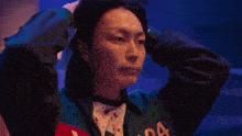 a woman in a green jacket is holding her head in pain .