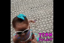 a little girl wearing sunglasses and a blue bow is standing on a tile floor .