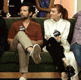 a man and a woman are sitting on a green couch with microphones in their hands .