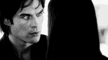 a man and a woman are looking into each other 's eyes in a black and white photo .