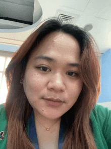 a woman wearing a green sweater and a necklace with a heart shaped pendant