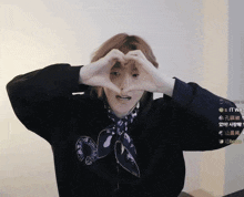 a person making a heart shape with their hands while wearing a shirt that says chrome hearts