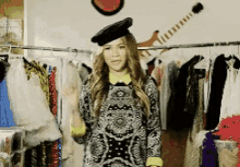 a woman wearing a beret is standing in front of a rack of clothes