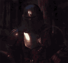 a close up of a person in armor with a red light behind them