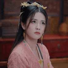 a woman wearing a pink dress and earrings has her hand on her heart
