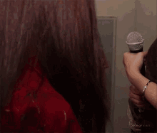 a woman is standing in front of a mirror holding two microphones and the words drop of a hat on the bottom