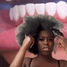 a woman is brushing her hair in front of a large mouth