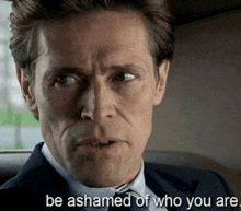 a man in a suit and tie with the words be ashamed of who you are below him