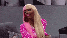 a woman with long blonde hair and pink lipstick is sitting on a couch .