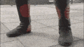 a person wearing a pair of black and red boots standing on a sidewalk