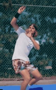 a tennis player wearing a headband and a white shirt is about to serve the ball