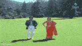 a man and a woman are dancing in a field . the woman is wearing a red dress .