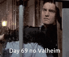 a man looking out a window with the words " day 69 no valheim " below him