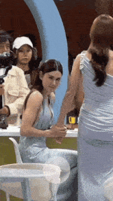 a woman in a blue dress is holding the hand of another woman in a white chair .