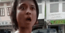 a woman with a surprised look on her face is standing in front of a store .