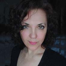 a woman with curly hair looks at the camera