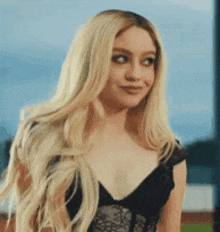 a woman with long blonde hair is wearing a black lace top and a wig .