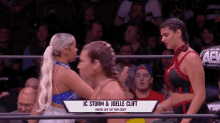 a couple of women are standing next to each other in a wrestling ring in front of a crowd .