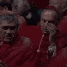 a group of men wearing red robes are sitting in a row .