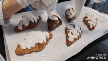a bunch of croissants are being decorated with white frosting and the words made in animotica can be seen in the corner