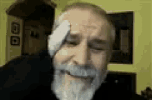a man with a beard is covering his forehead with a white cloth .