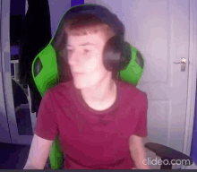 a young man wearing headphones and a red shirt is sitting in a green gaming chair .