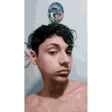 a young boy without a shirt is taking a selfie in front of a wall with a picture of dolphins on it
