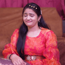 a woman in a red dress is sitting on a couch and making a face