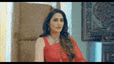 a woman in a red dress and necklace is sitting in a chair .