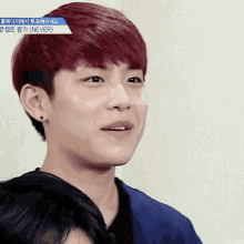 a young man with red hair is smiling and looking at the camera .