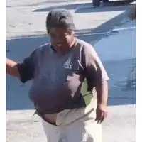 a man in a t-shirt and white pants is standing on a sidewalk .